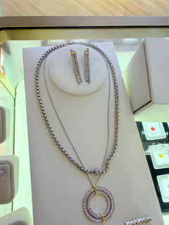 Original reference photo: Double Bar Pendant Necklace is the inner chain with the large concentric white-stone circular pendant and gold-tone bridges. Other jewellery appears on the display.
